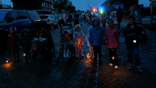 Kinderen met regenjas en lampionnen