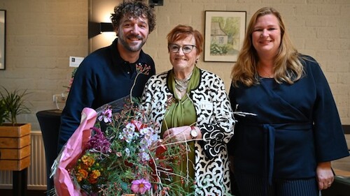 Fien Wonen en Huurdervereniging de Jupiter samen met een bos bloemen