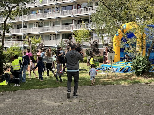 Spelende kinderen en ouders bij een groot opblaasbaar springkussen op een grasveld.