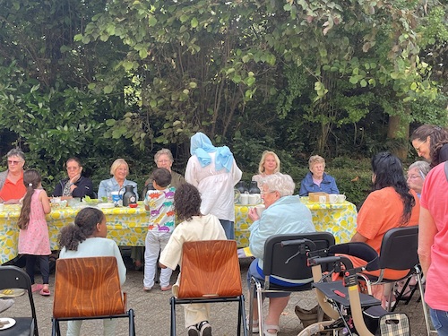 Medewerkers van de deelnemende organisaties zitten met bewoners van de peulenflat aan een grote tafel